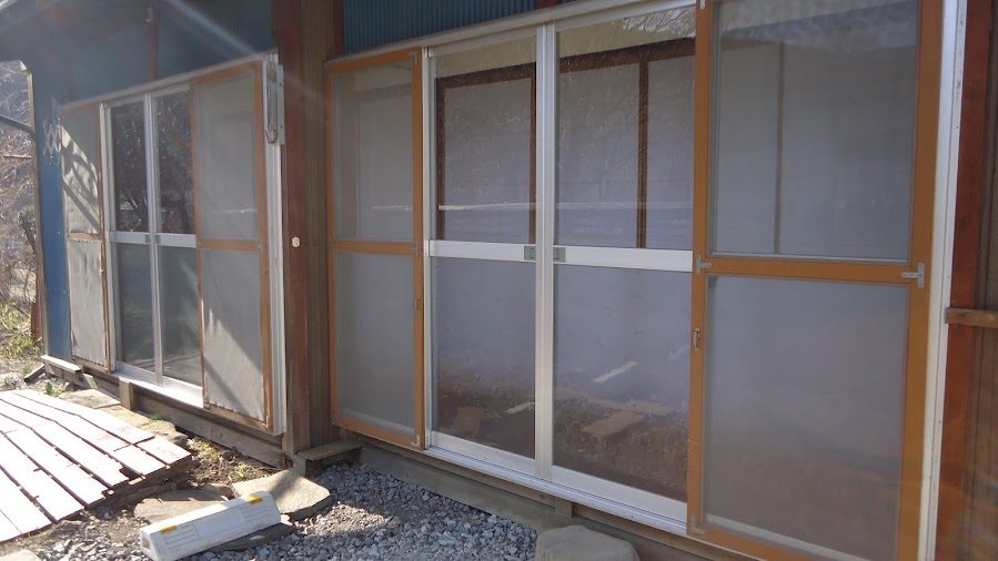 施工前：破れて色あせた古い網戸が並ぶ窓